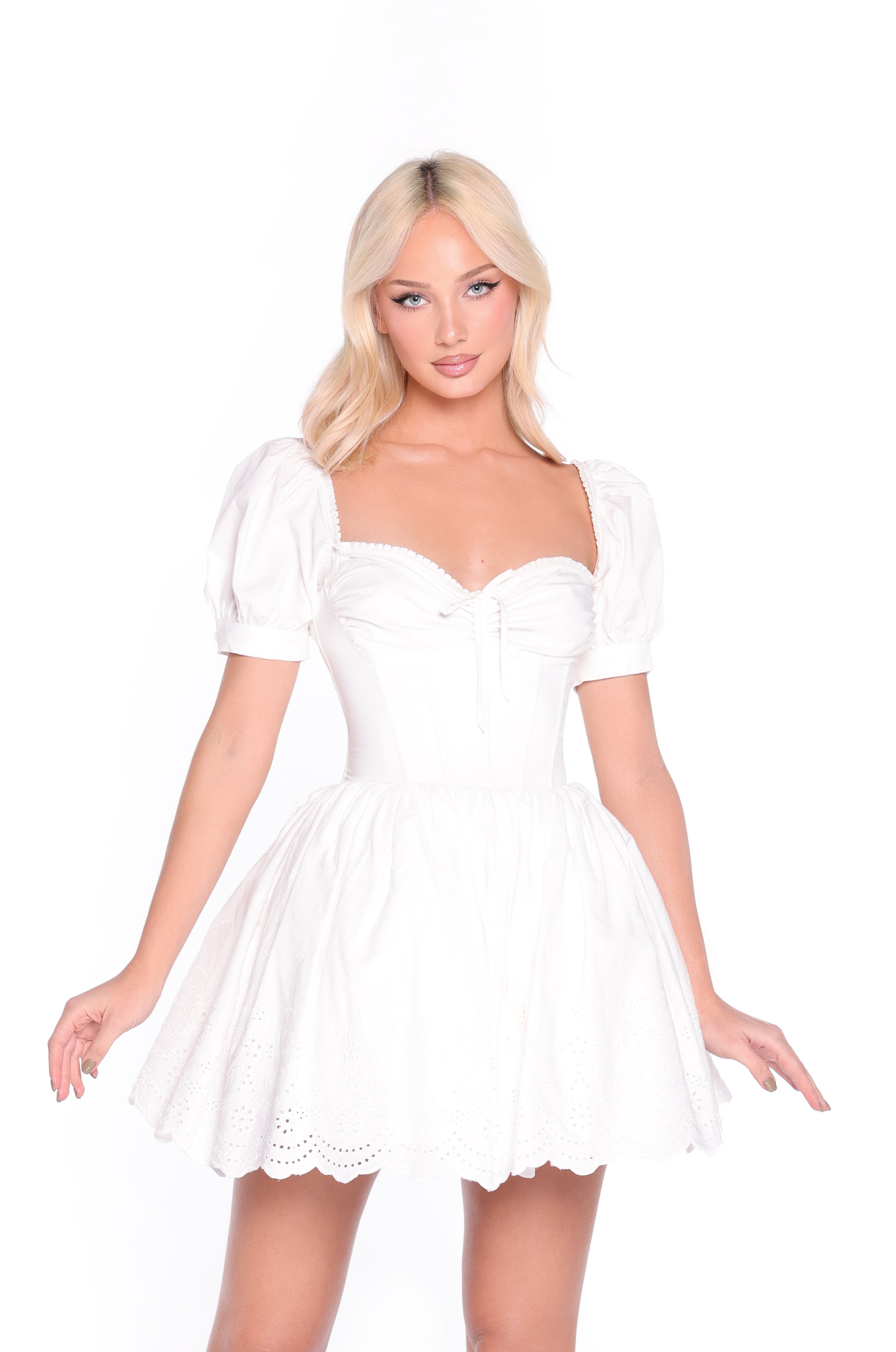 Woman wearing the Celine Fit-and-Flare Short White Grad Dress with puff sleeves and an eyelet skirt, posing against a plain white background—perfect for graduation.